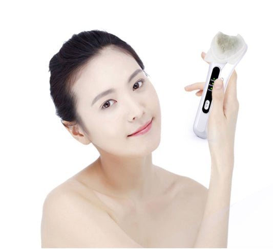"Model using a white heated facial cleansing brush near her cheek, demonstrating skincare routine"