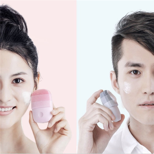 Mulher e homem segurando escova facial de silicone portátil, sorrindo enquanto limpam o rosto com espuma — ideal para cuidados com a pele em casa ou em viagens.