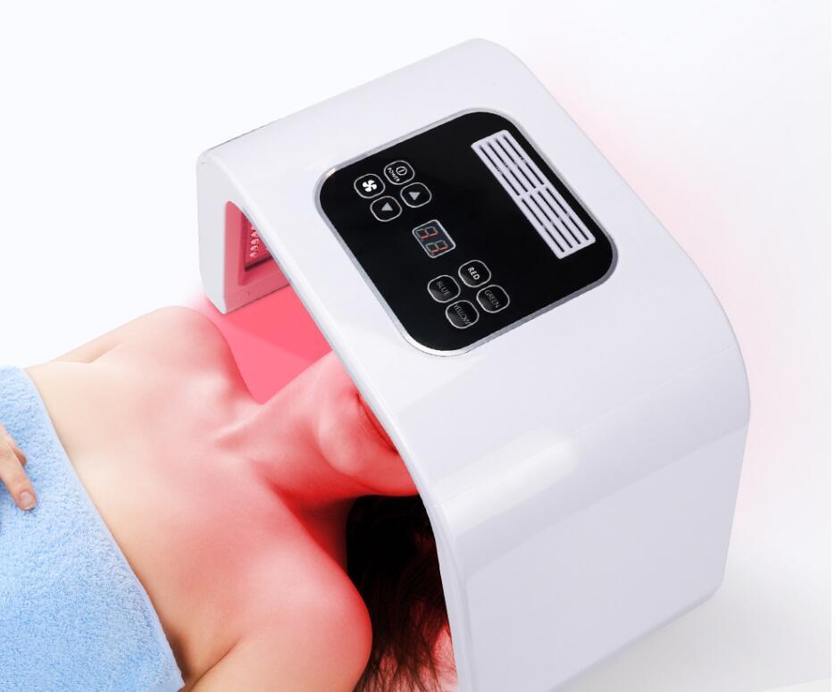 Woman undergoing red light facial treatment using a white LED therapy mask device. Close-up of control panel and red light emission on skin during skincare session.