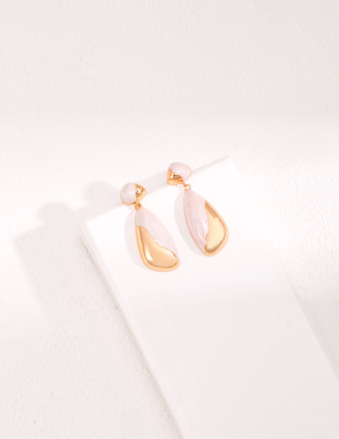 A pair of minimalist drip glaze earrings handcrafted in 18ct gold vermeil and sterling silver, photographed on a soft neutral background.