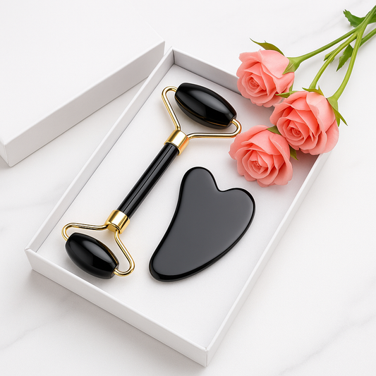 Black obsidian facial massage set featuring a jade roller and gua sha stone, elegantly arranged beside a gift box and pink roses — ideal for natural skincare rituals and self-care.