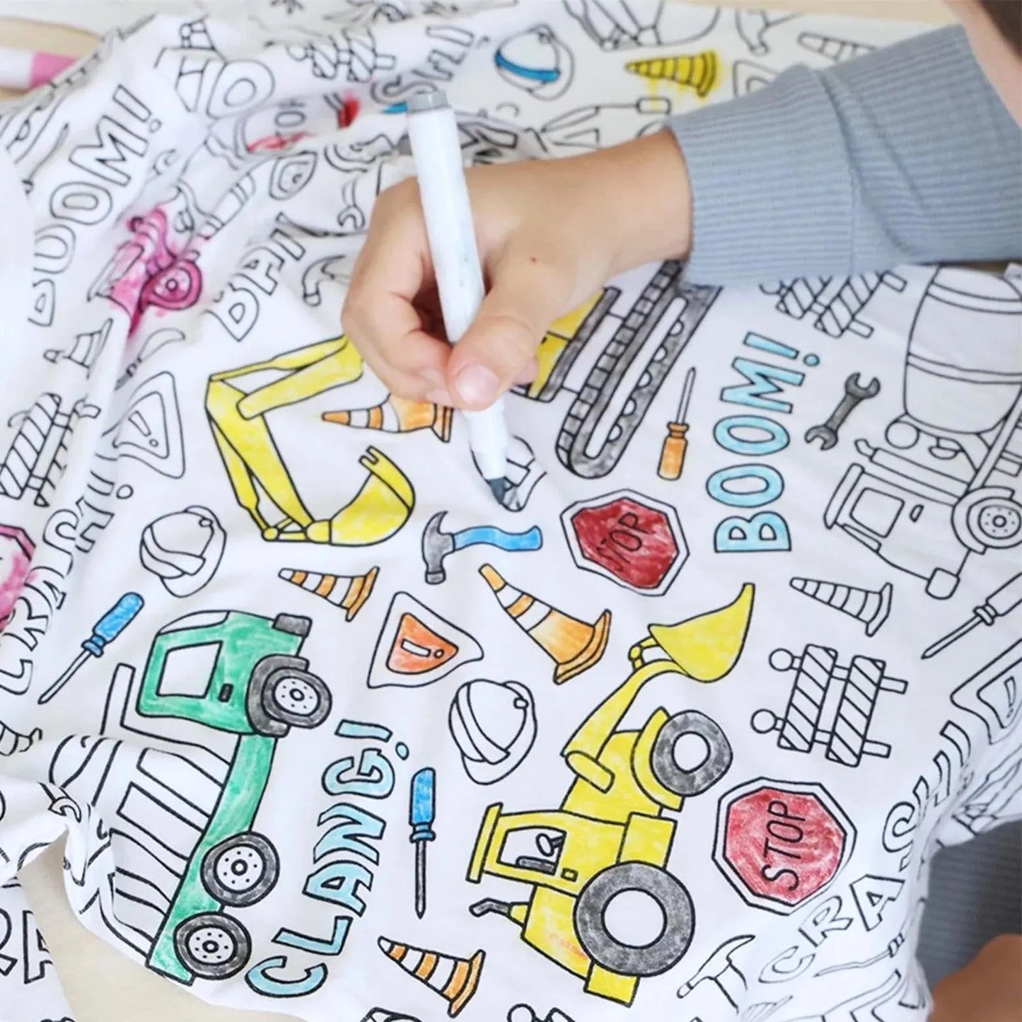 Child colouring construction-themed pyjamas with marker – creative activity.
