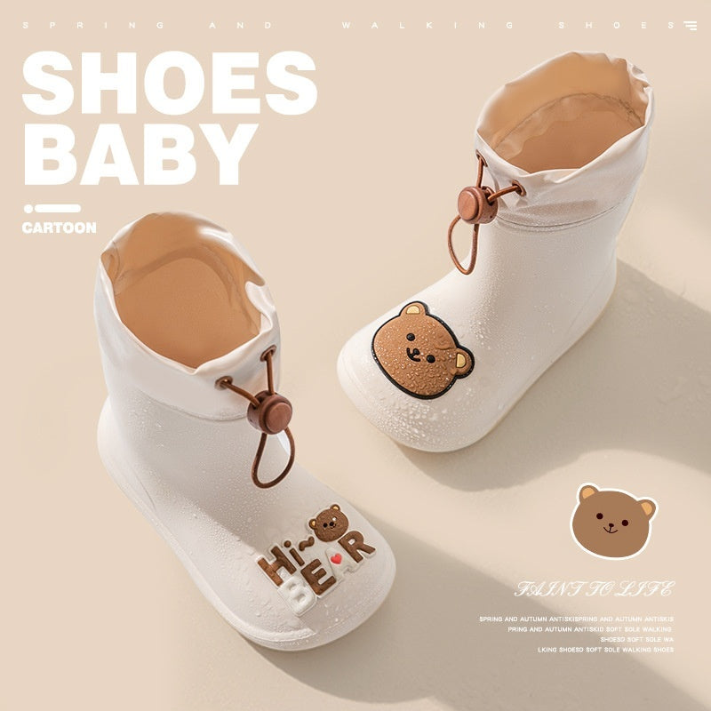 “White baby rain boots with teddy bear face, ‘Hi Bear’ lettering and drawstring elastic top – waterproof and non-slip PVC sole”

